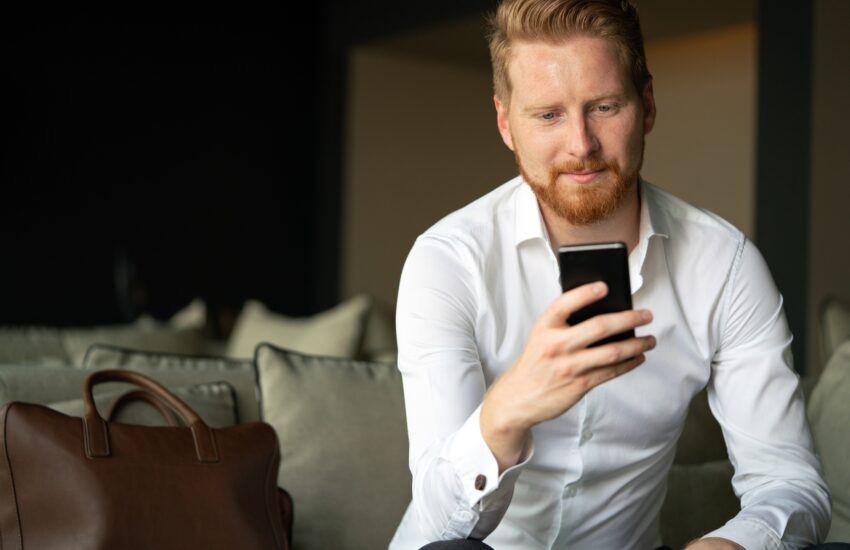 Young businessman sending message with mobile phone