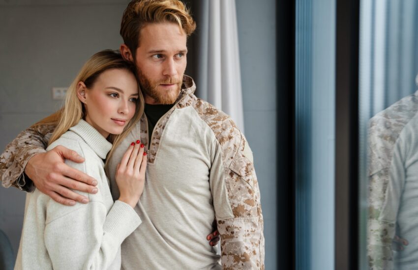Beautiful young happy couple hugging and looking out window indoors