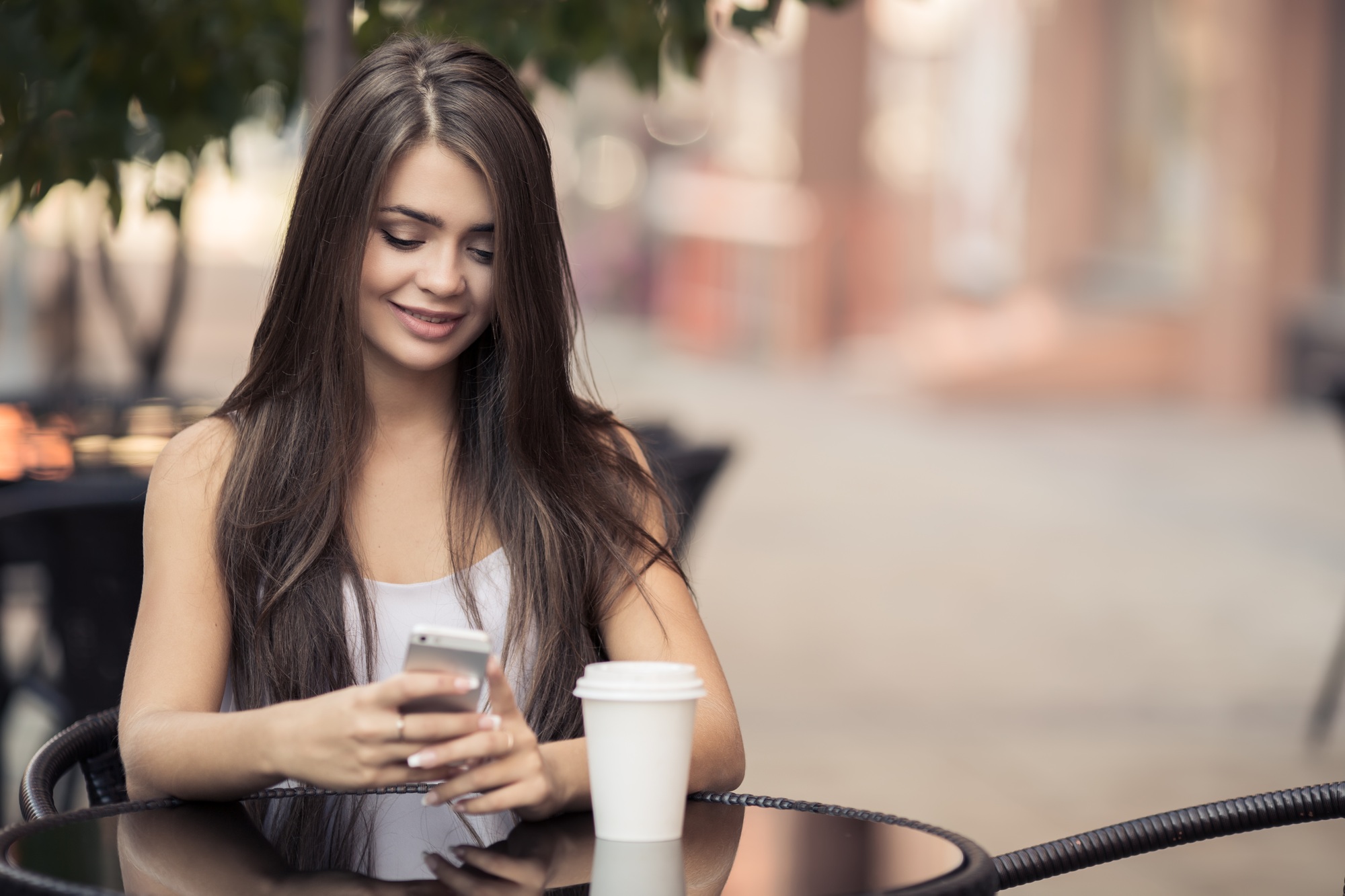 Young Beautiful Woman In Coffee Shop Sending Sms On Smartphone.
