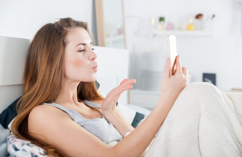 Young girl in bed taking selfie send kiss