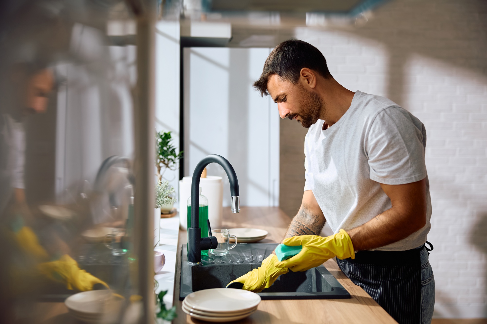 Young man doing dishes in the kitchen.